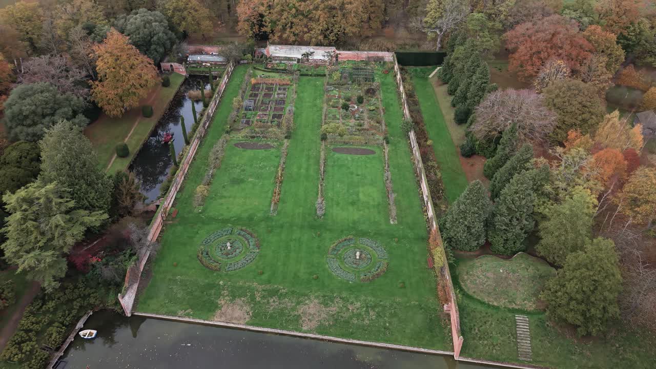 Gardens And Parkland Near The Red-brick House And Its Moat In Kentwell Hall In Long Melford, Suffolk, England. Aerial Drone Shot