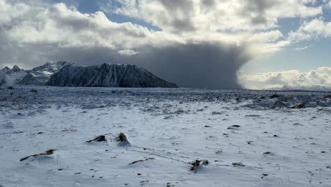 Schwenkaufnahme-Einer-Schneebedeckten,-Kargen-Landschaft-In-Der-Arktis-Mit-Bergen-Und-Sturmwolken-In-Der-Ferne,-Teilweise-Bewölkter-Tag