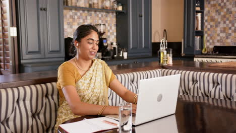 working from home, indian woman in traditional sari using laptop and taking notes