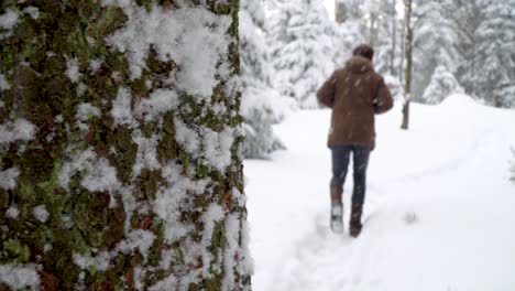 caucasian man in casual winter clothing walking along snowy path in german harz mountains while it is snowing