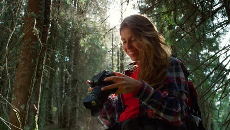 girl with photo camera standing in forest. woman holding professional camera