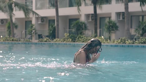 brunette-shakes-hair-in-pool-against-palm-trees-slow-motion