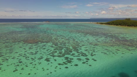 一架无人机在热带岛屿上飞过浅海湾的珊瑚礁