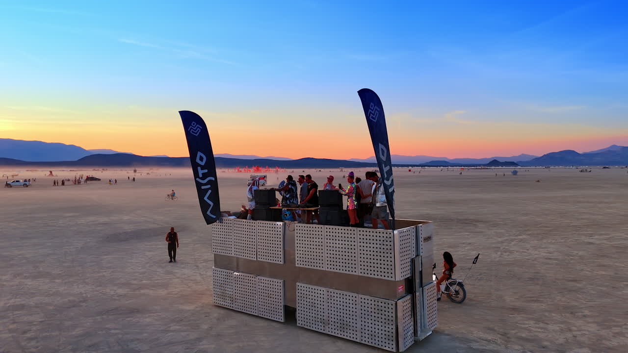 Nevada, USA, 14 August 2025: DJ stage and participants at Burning Man festival in Nevada desert.. Festival goers gather near a DJ stage with flags on the playa