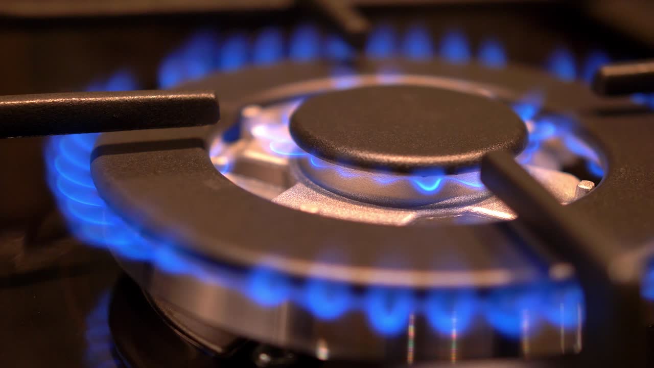가스 스토브가 켜지고 꺼지고 파란 불꽃이 어 속에서 불타고 있습니다.