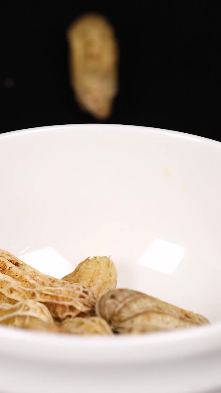Arachidi che cadono in una ciotola bianca