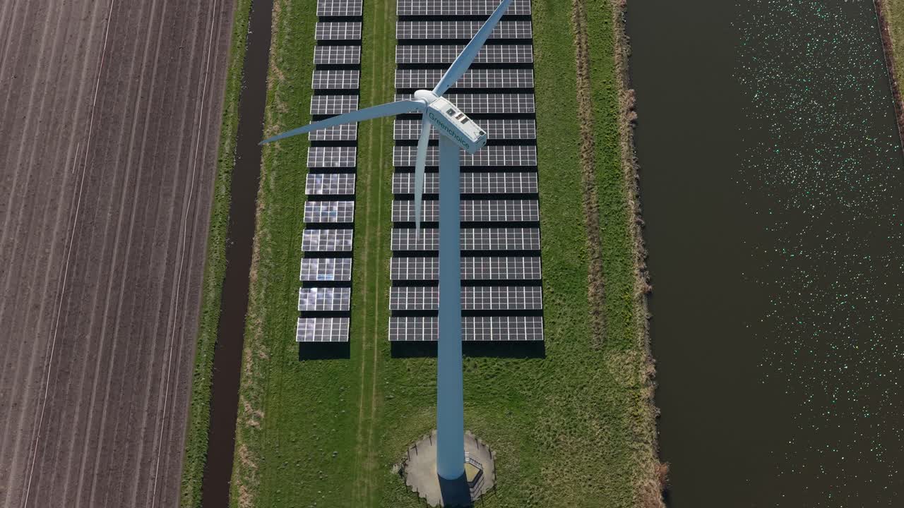 Vista aerea di una turbina eolica e pannelli solari che generano energia rinnovabile.
