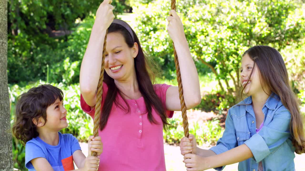 아이 들 이 공원 에서 어머니 를 스 ⁇  에 밀어 넣고 있다