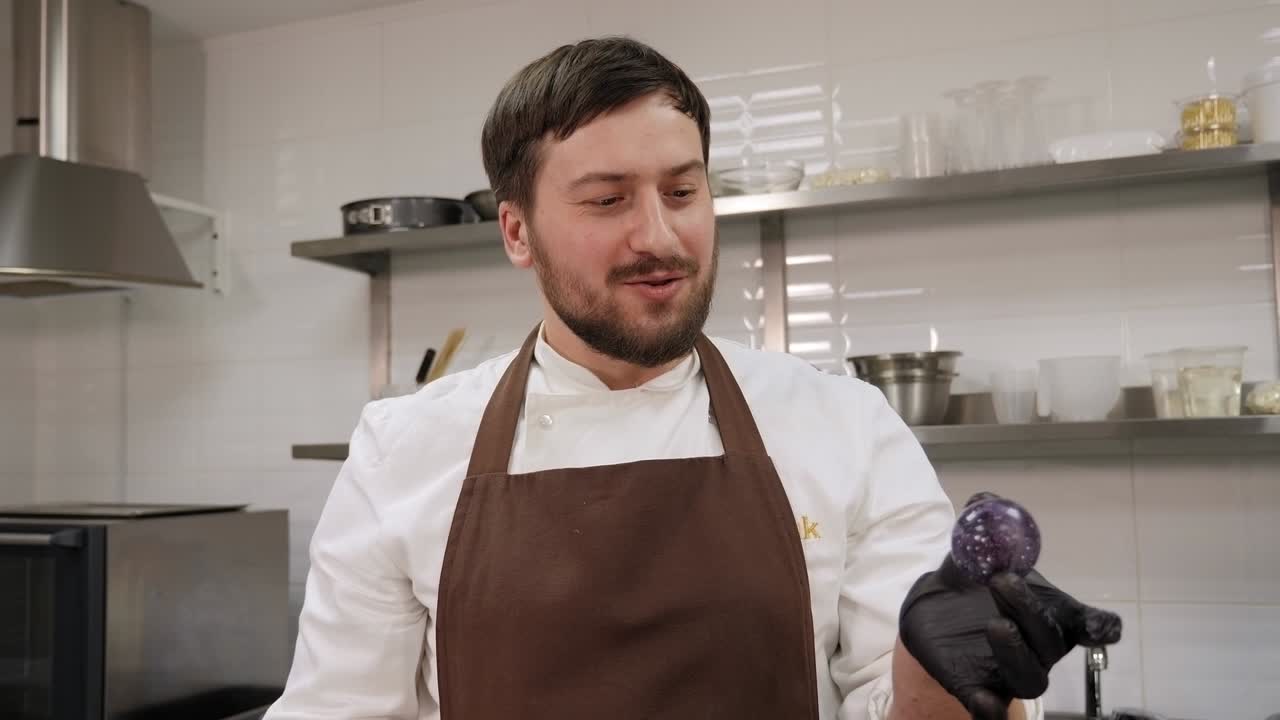 un chef de pastelería tiene un caramelo de chocolate hecho a mano o praline en una pastelería.