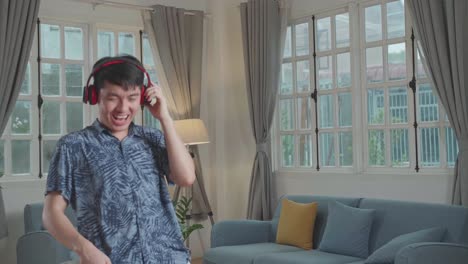 Cheerful Man Cleaning Up His Home And Singing, He Is Using The Vacuum Cleaner As A Guitar And Microphone