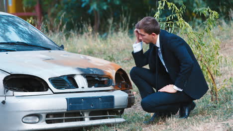 a man in a suit inspects a car after an accident 1