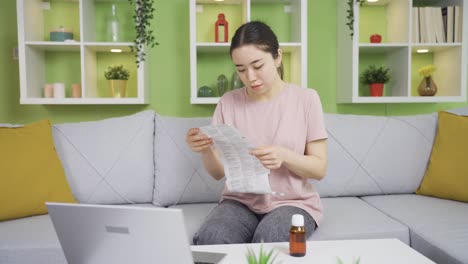 아시아 젊은 여성이 집에서 의약품  ⁇ 플 ⁇ 을 읽고 있습니다.
