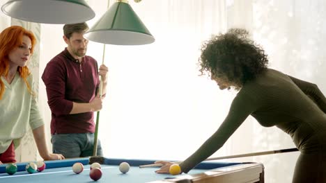 back light of a woman playing pool with friends