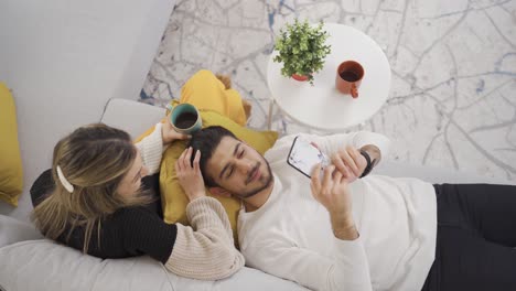 Marido-Y-Mujer-Felices-Disfrutando-De-Pasar-Tiempo-Juntos-Mientras-Se-Sientan-En-El-Sofá-Y-Se-Relajan.