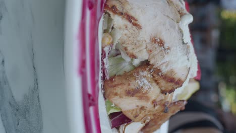 close-up of a grilled chicken wrap with fresh lettuce and sauce