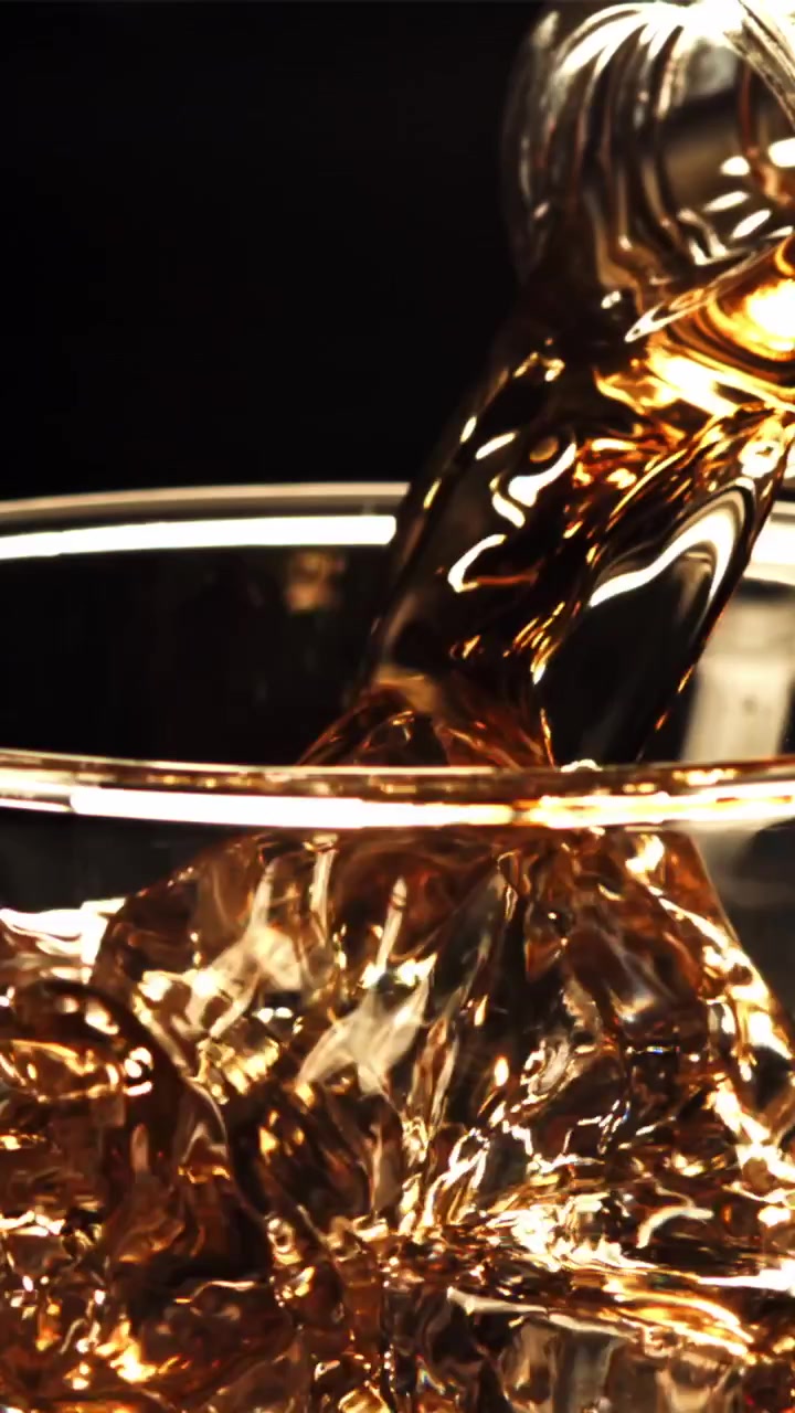 Whiskey dorato versato in un bicchiere con ghiaccio