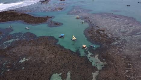 tourists and boats at natural pools with coral reefs