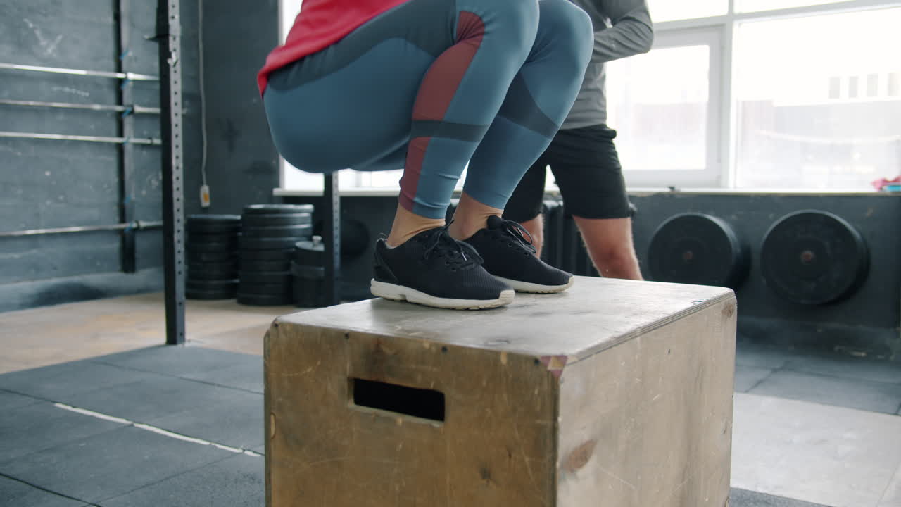 Woman Doing Box Jumps with Trainer in Gym