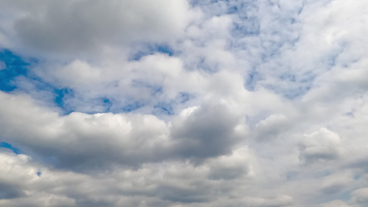 Soft fluffy clouds covering the sky. Cloudscape formation in the atmosphere at daytime. Low angle view. Timelapse.
