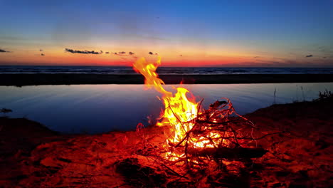 video de movimiento de una hoguera ardiente en la orilla de un lago en irbes ieteka, kempings, letonia durante la puesta de sol