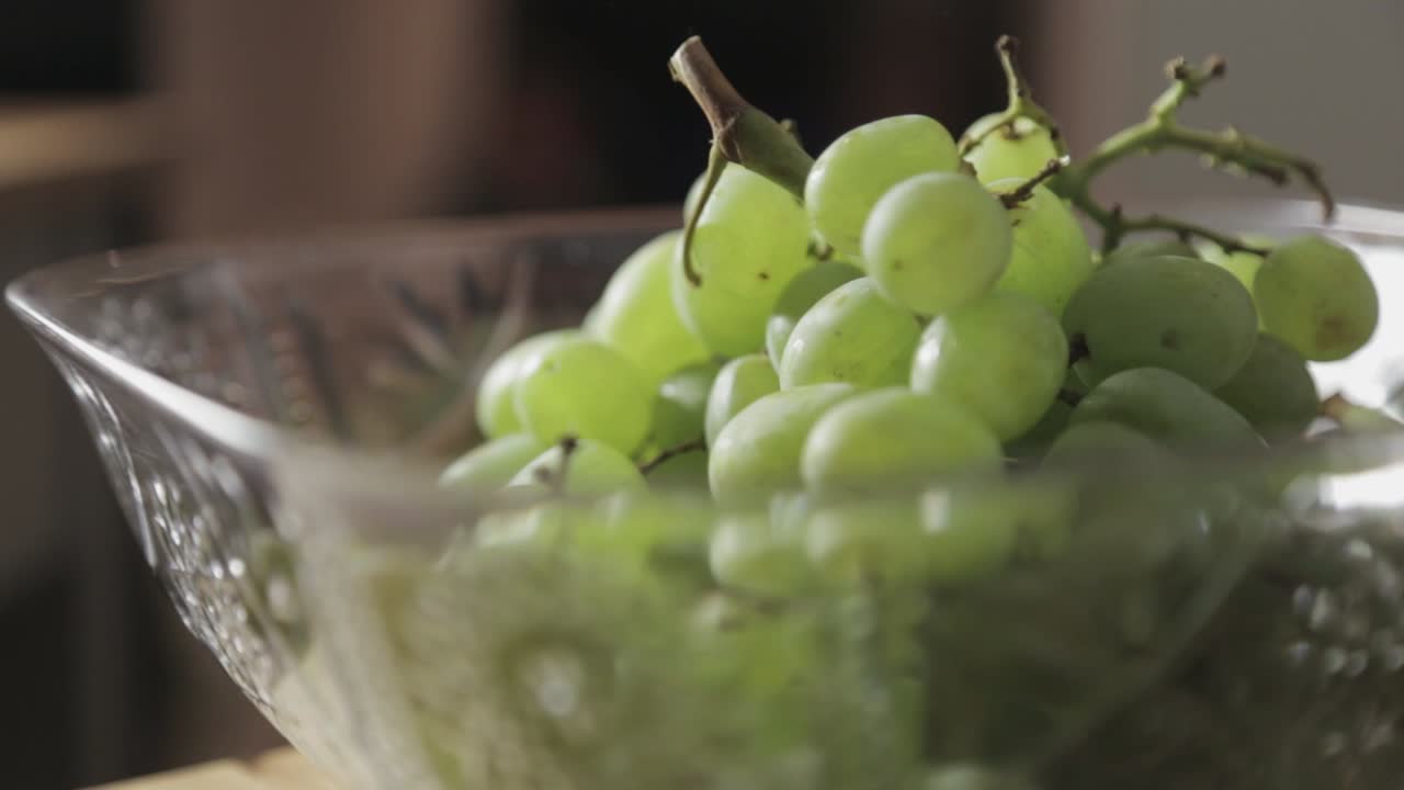 흰색 투명한 그릇 안에 달콤한 녹색 포도 하나를 집어 들고 있는 소녀의 손 - 클로즈업 샷