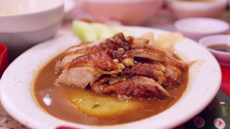 Dipping-a-slice-of-Peking-duck-in-a-spicy-sauce-that-is-served-in-a-platter-at-a-restaurant-in-Bangkok,-Thailand