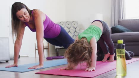 madre y hija caucásicas practicando yoga en la sala de estar