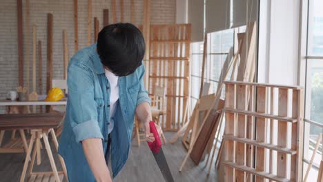 carpenter man working hand saw on wood craft to produce construction material or wooden furniture