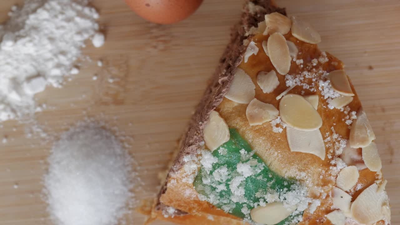 Rosco de Reyes slice with almonds on wooden board, festive baking mood