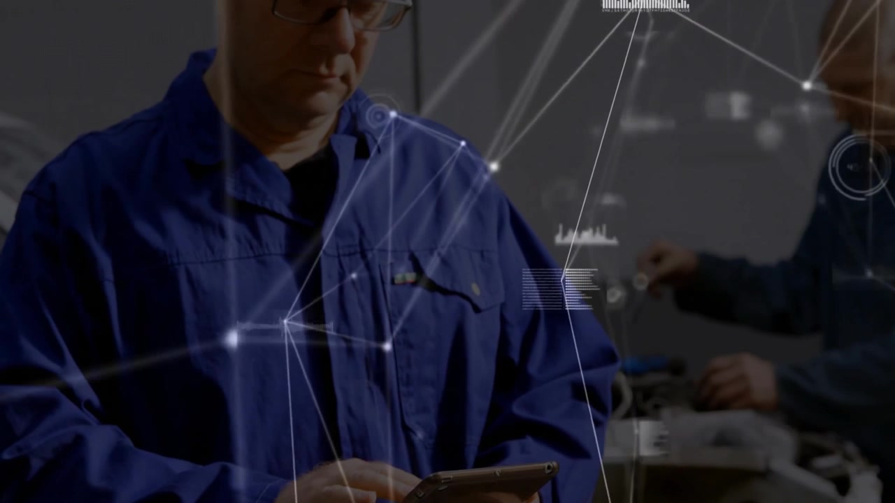 Technician tapping tablet and showing data overlays linking garage while coworker inspecting engine