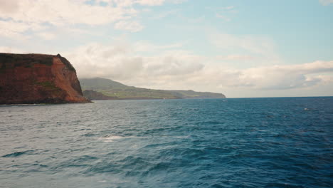 Slow-motion-view-of-high-cliffs-rocky-coastline-from-the-ocean