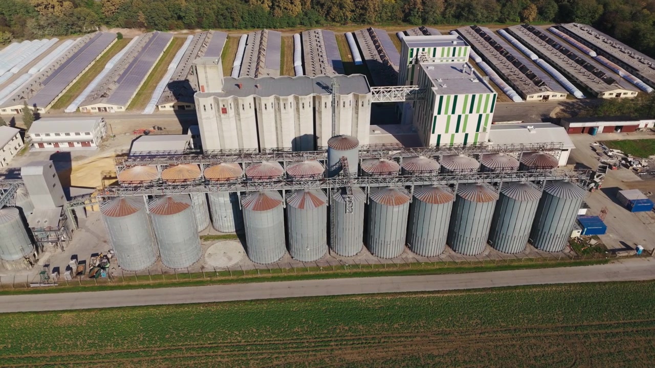 Eine Luftaufnahme zeigt Getreidesilos in einer landwirtschaftlichen Lageranlage, umgeben von Feldern. Lastwagen sind