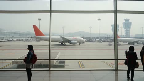 people waiting in an airport with airplanes