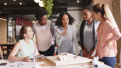 Diverse-team-of-focused-female-architects-discussing-architectural-model-at-work,-in-slow-motion