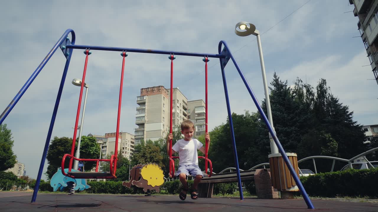 A boy swings on a swing in the city 02