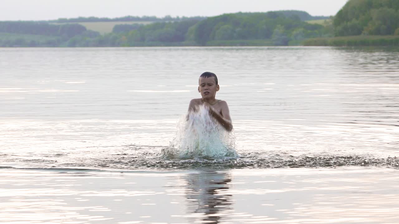 Boy are having fun and splashing in the water. Summer holiday concept. Slow motion.