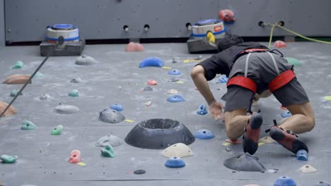 asian man rock climbing indoors; look up shot