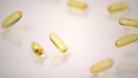 slow motion macro of yellow pills dropped onto white background