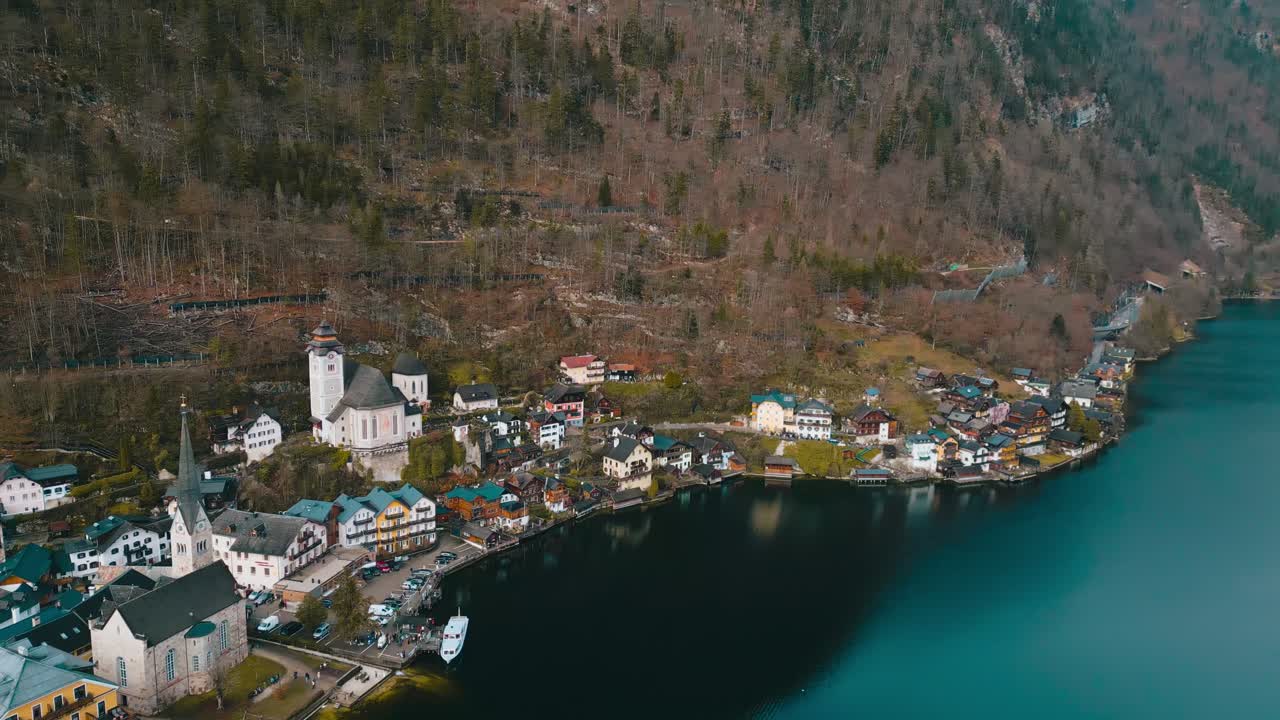 Elokuvamainen 4K-dronekuvamateriaali panoroi ylöspäin ja pois päin Hallstattin alppikylän kirkosta, paljastaen hitaasti pastellinväriset talot ja tämän ikonisen UNESCO-kohteen majesteettiset vuoret