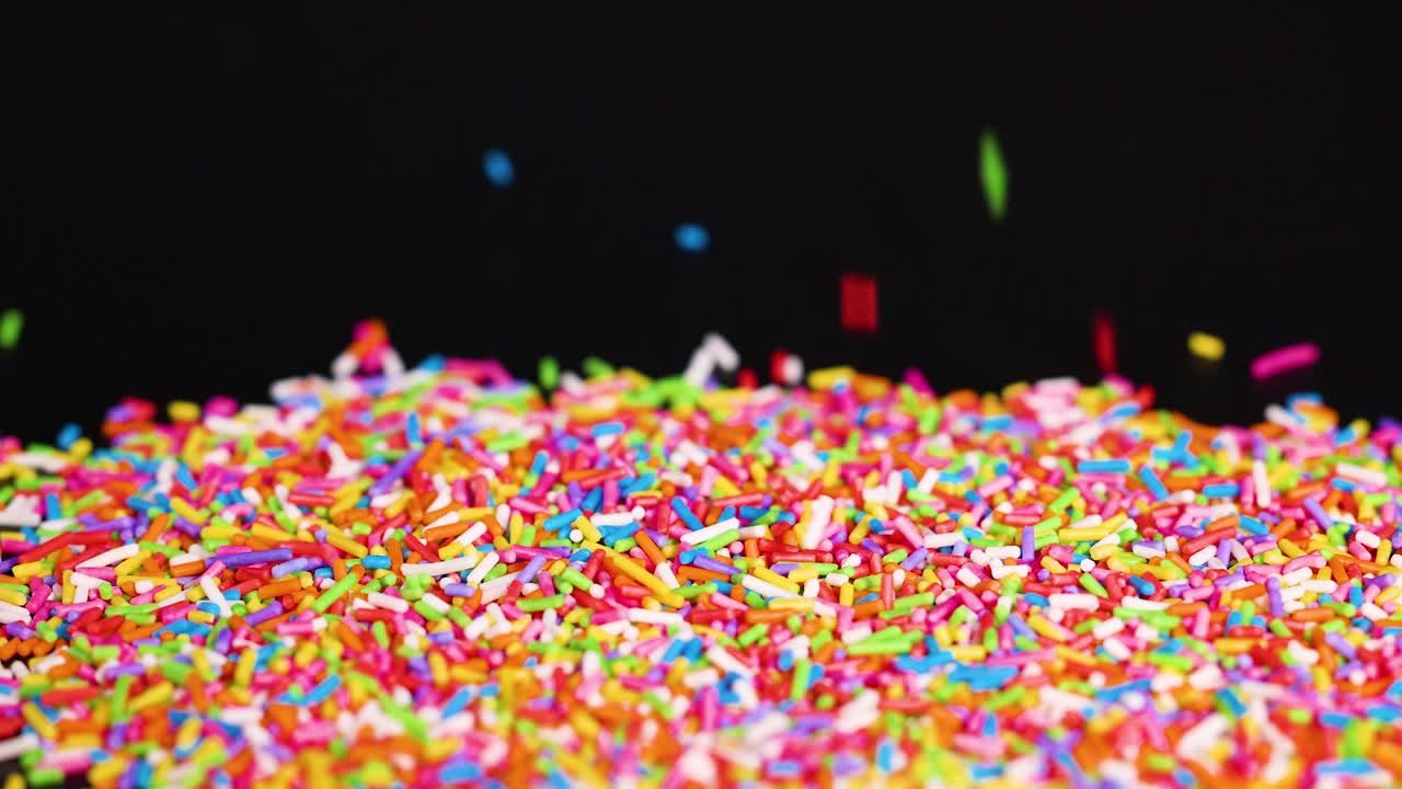 Vibrant sprinkles cascade against a dark background