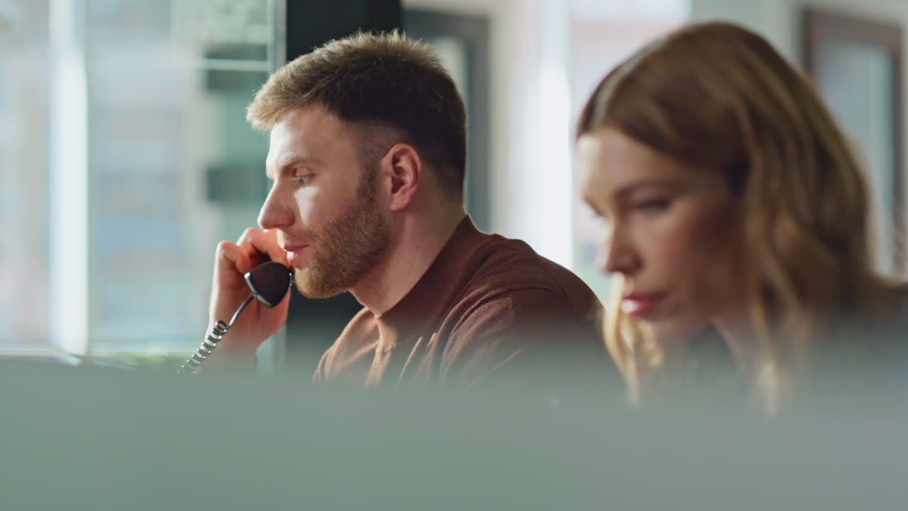 Help desk operators talking phone in office workplace closeup. Two specialists