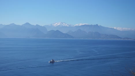 Establishing-shot,-boat-in-the-Mediterranean-sea,-toros-mountain-range-in-Antalya-Turkey