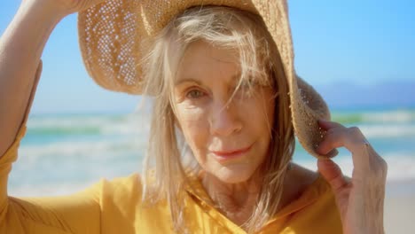 front view of active senior caucasian woman in hat standing on the beach 4k