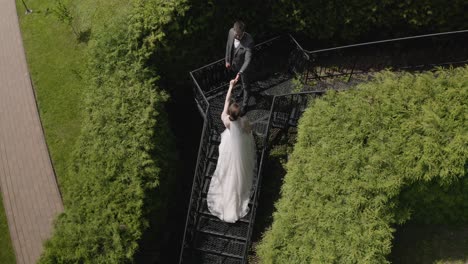 Newlyweds,-caucasian-groom-with-bride-stay-on-stairs-in-park,-wedding-couple,-man-and-woman-in-love