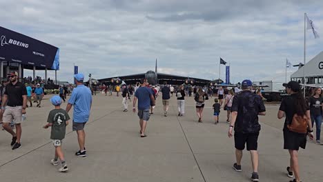 airshow attendees walk near a boeing b-52 bomber and exhibit booths on a cloudy day, enjoying displays and aviation attractions.