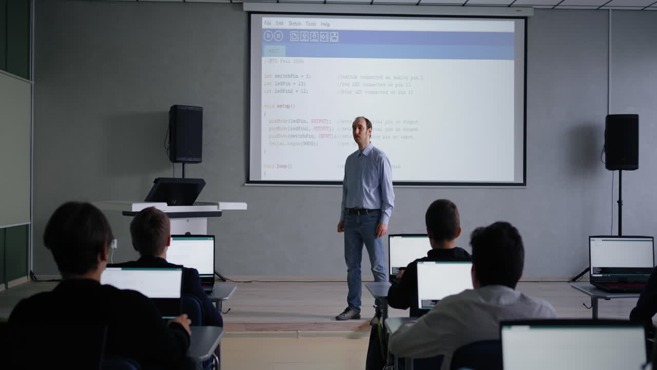 교사가 교실에서 학생들에게 코딩 강의를 하고 있습니다.