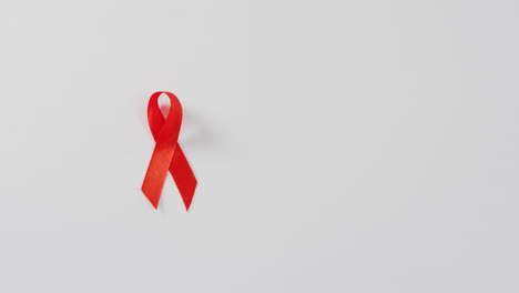 Video-of-close-up-of-red-cancer-ribbon-on-white-background