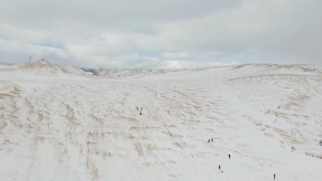 Vista-Aérea-De-Personas-En-Trineo-En-El-Lago-Nacional-Dunas-De-Osos-Durmientes,-Michigan