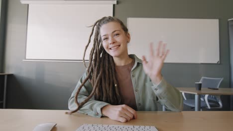 niña con rastas haciendo una presentación sentada en una mesa en clase