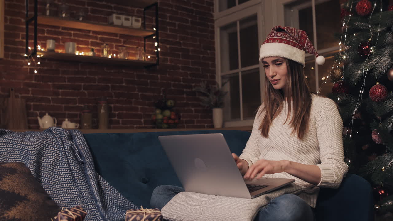 Woman in Santa Hat Using Laptop at Home During Christmas